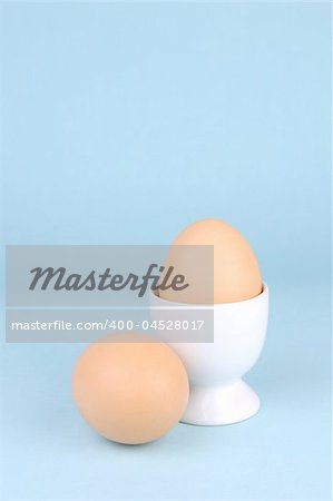 Hard boiled eggs and egg cups isolated against a blue background