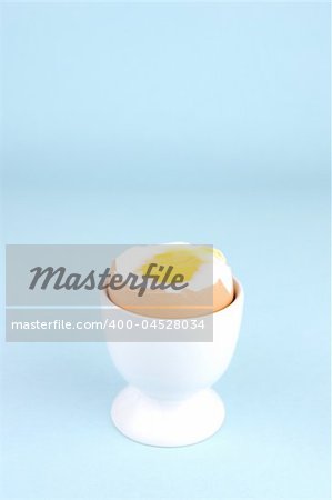 Hard boiled eggs and egg cups isolated against a blue background