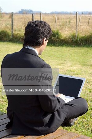 A young businessman working on a laptop in a rural property