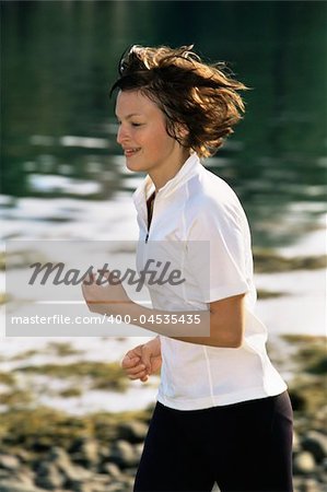 Young woman running along water's edge