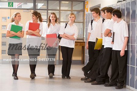 Teenage boys watching girls walk down a school corridor