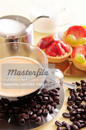 Freshly brewed coffee with a selection of pastries and cakes. Coffee beans are scattered for extra effect.