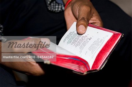 Two hands holding an old, well-used prayer book at a Methodist church service on Sunday are symbolic of faith of South African people. Note: shallow depth of field is focused on just the thumb and the nearby text.