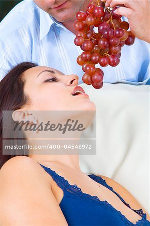 Close up portrait of nice young brunette getting tempted with grape