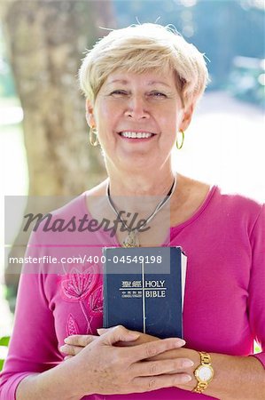 elderly woman reading bible in the garden