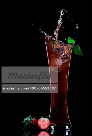 View of strawberry juice splashing out of glass on black back