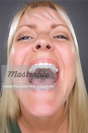 Laughing Blond Woman with Funny Face against a Grey Background.