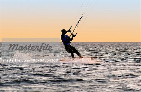 Silhouette of a kitesurfer on waves of a gulf