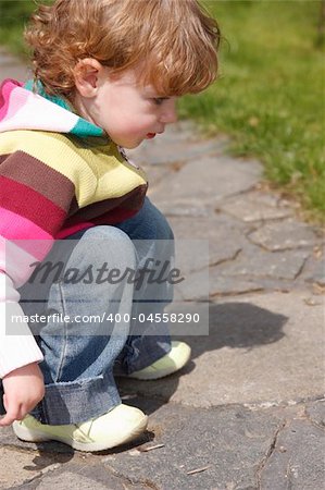 A child on the stone path in a green garden.