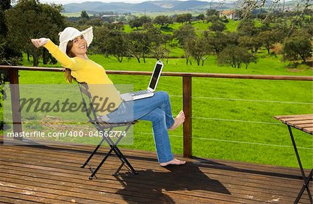 Woman enjoying a beautiful day with a laptop on her home-field