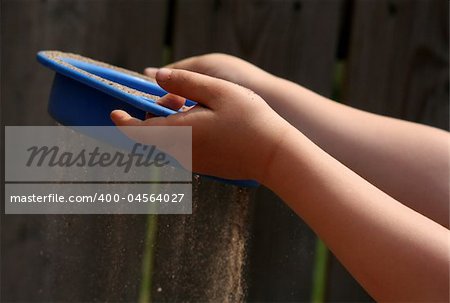 A childs hand sieving sand with a sieve.