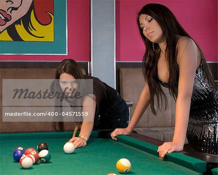 two cute girls playing on a billiard