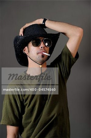Portrait of young male smoking with sunglasses and cowboy hat