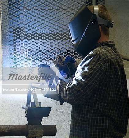 Welder at work, illuminated by an acetylene welding torch.  All work depicted is authentic and in compliance with industry code and safety regulations.
