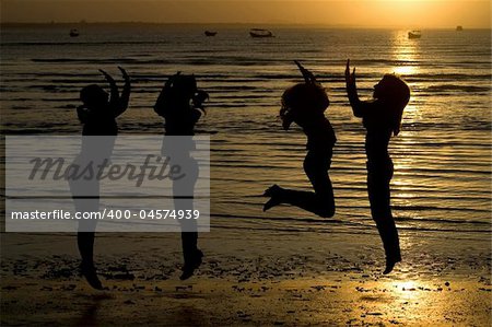A silhouette of girls jumping in water.