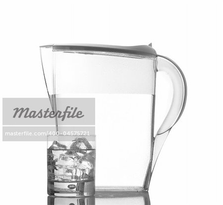 Pitcher and glass with ice cubes of mineral water reflected on white background