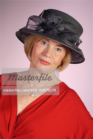 portrait of very attractive older woman wearing black hat and red dress