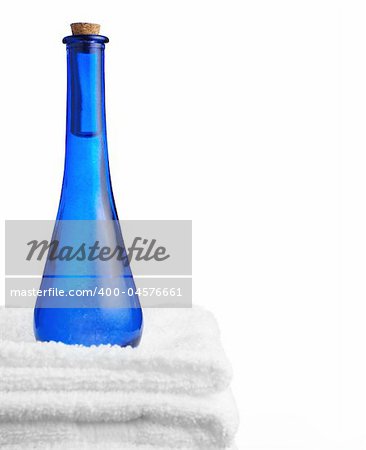 Blue glass corked bottle and towels against white.