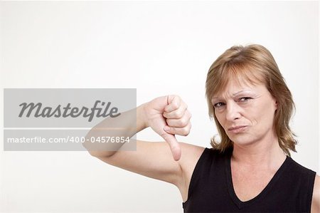 Mature adult female frowning while giving a thumb down signal