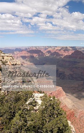 A shot of a partially cloud covered Grand Canyon from the South Rim, looking out on a trail to the Colorado.