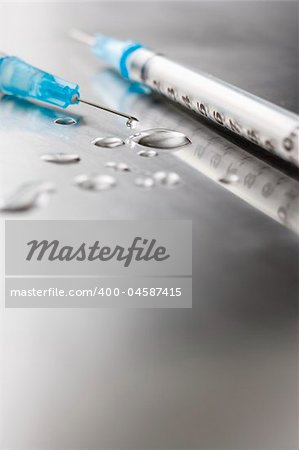 Needles on stainless steel table with  drops of liquid