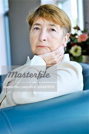 Sad elderly woman sitting on a couch indoors