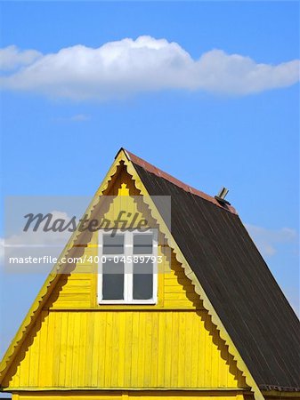 wooden cottage fragment against blue sky with light clouds