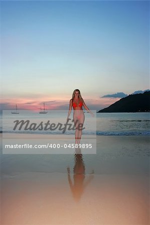 Girl standing on the sunset beach in thailand