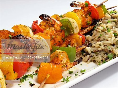 Spicy shrimp kebabs with colorful bell peppers, onions, and rice pilaf.