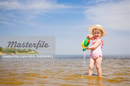 small girl with watering-pot on the seashore