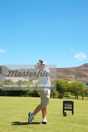 Young male golfer hitting the ball from the fairway on a beautiful summer day