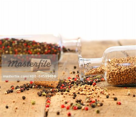 Peppercorns in glass bottles on rustic wood table
