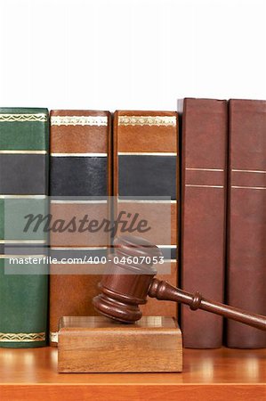 Wooden gavel from the court and old law books reflected on white background. Shallow depth of file