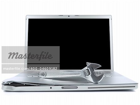 A spanner over a damaged laptop isolated over white background. Black copy space on screen.