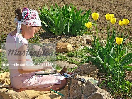 young painter paints near yellow tulips
