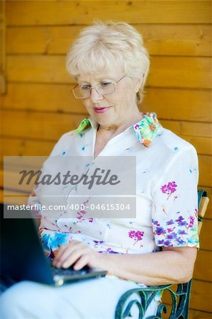 The elderly woman writes  on the computer