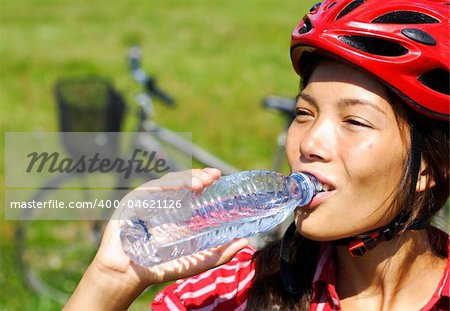 Beuatiful young woman enjoying a bottle of water outdoors on a bike trip in Denmark.