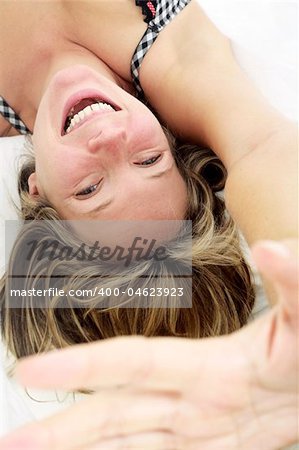 Woman in bed smiling with her hand held up to the camera