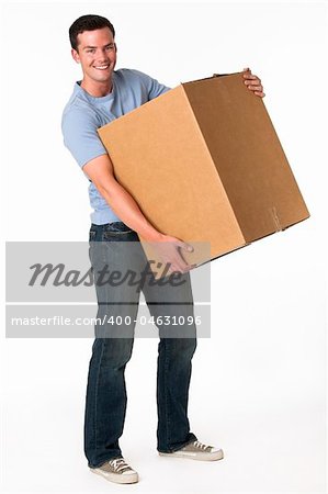 A man is holding a moving box and smiling at the camera.  Vertically framed shot.