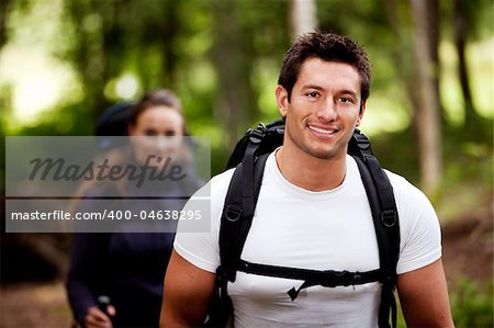 A portrait of a male hiking in the forest with a female