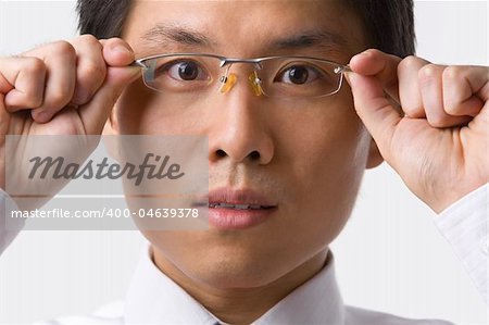 A young Asian businessman gazing at camera while holding glasses to camera