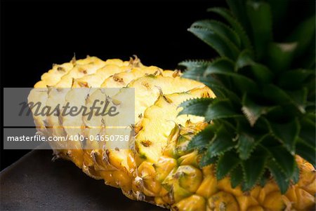 ripe vibrant pineapple sliced on a black plate