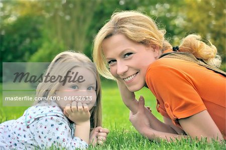 Young mother and daughter laying on the grass
