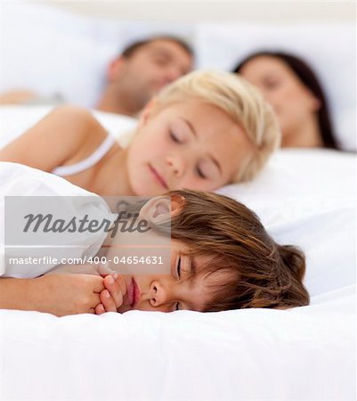 Young family sleeping together in parent's bed