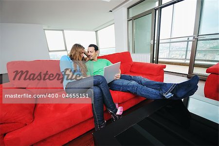 happy young couple have fun and relax at comfort bright appartment and work on laptop computer