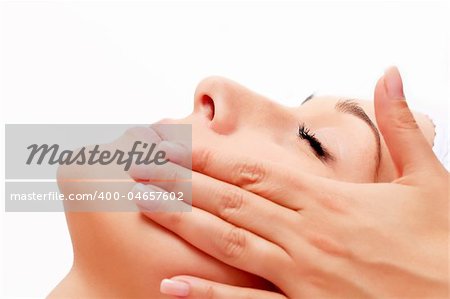 A young woman relaxing at a health spa while having a facial treatment and hands massaging.