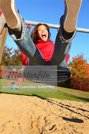 Swing. Happy young woman swinging on a playground.