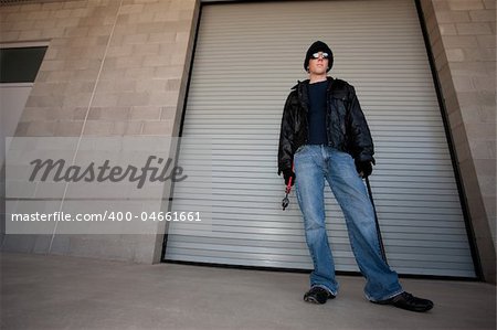 Burglar with tools in front of industrial door