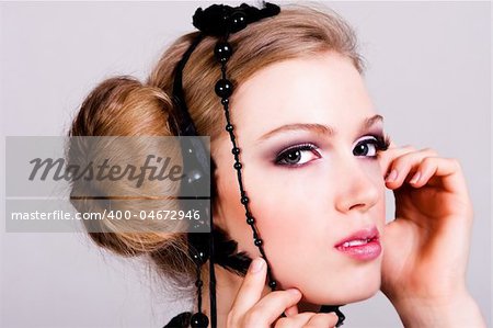 Attractive young woman wearing black feather and pearl hair dressings. Horizontal shot.