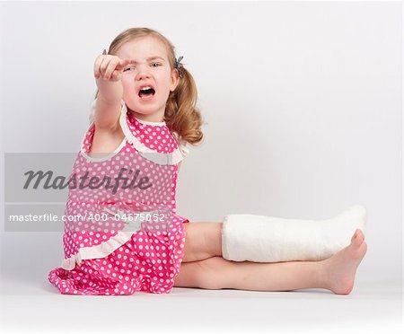 Little girl injured with broken ankle sitting on white backgound.